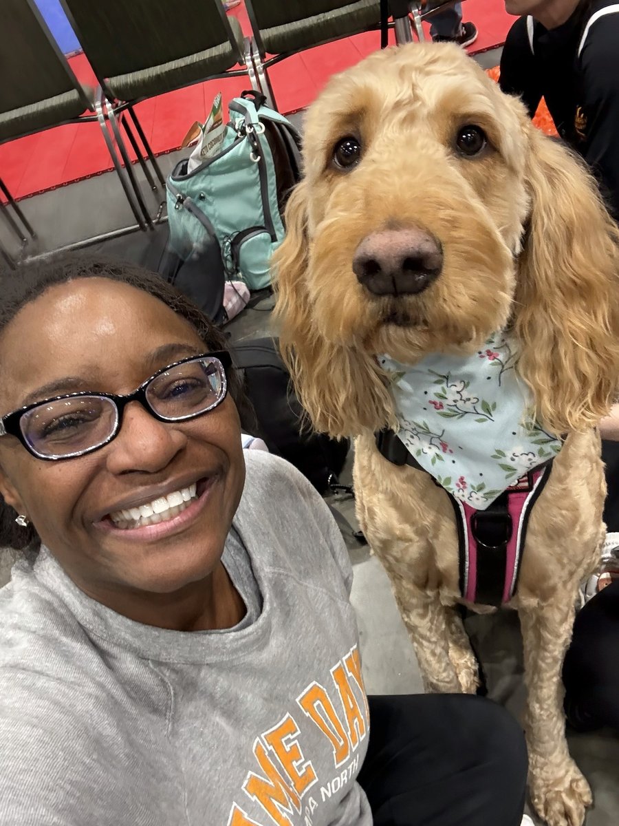 Alva at a volleyball tournament, smiling next to a goldendoodle.
